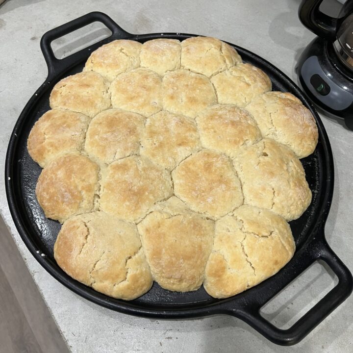 Homemade biscuits on a cast iron skillet sitting on the counter